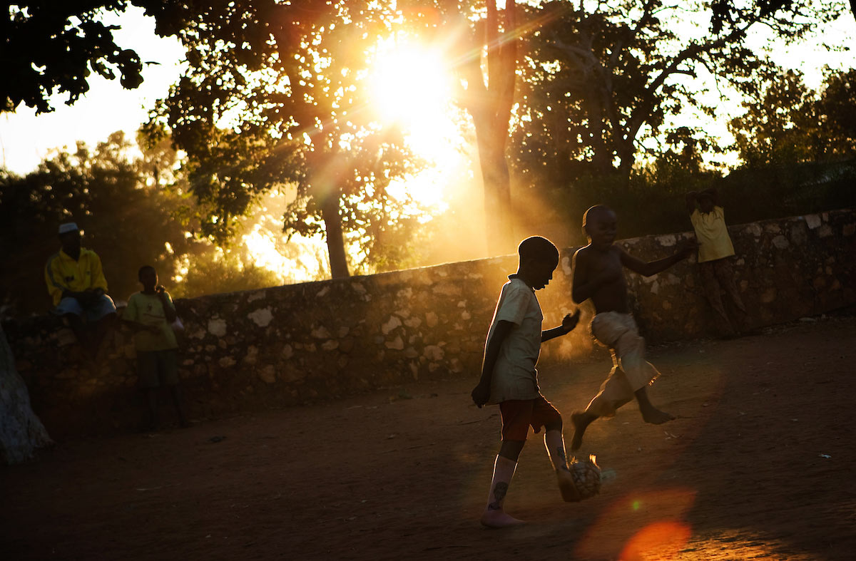 Kids playing soccer at sunset.